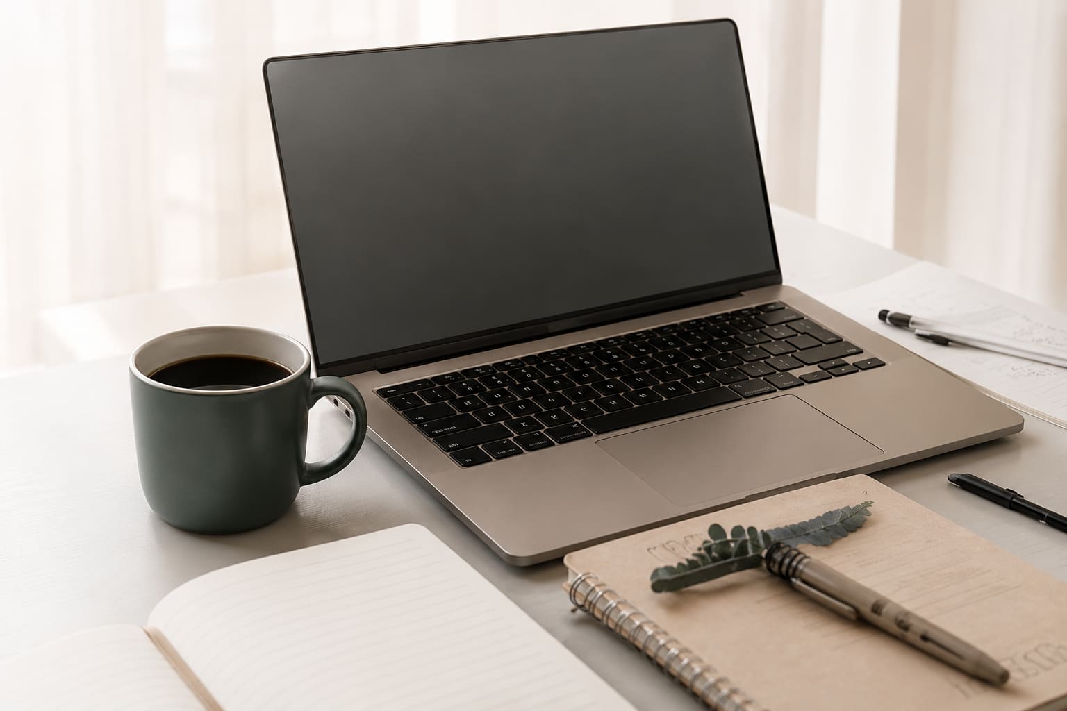 Laptop and notebook on a desk, representing the Elowen Library resources